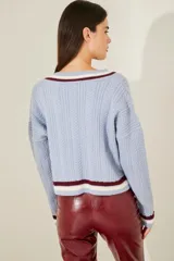 Cardigan celeste de punto trenzado, con escote en V y botones metálicos. Presenta ribetes a contraste en cuello, puños y bajo.