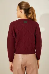 Sweater color borgoña de punto con cuello redondo, diseño de rombos con tachas aplicadas y detalle de corazones de cuero en la espalda.