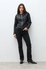 Chaqueta negra de eco cuero con cierre frontal y cuello redondo. Presenta paneles con diseño geométrico de tiras en relieve en el frente y mangas.