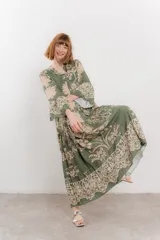 Vestido largo azul con estampado floral en tonos beige, confeccionado en viscosa. Presenta escote en V, botonadura completa en el frente y mangas largas con volados.