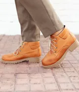 Bota acordonada color marrón claro de cuero, con suela de goma color beige y cordones finos blancos.