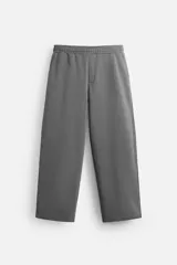 Pantalón jogger gris de corte ancho, confeccionado en tejido de algodón con interior de rizo. Cuenta con cintura elástica ajustable con cordón interior, bolsillos laterales y bolsillo trasero de parche.