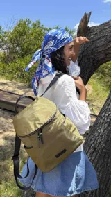 Mochila urbana de color verde oliva, con correas negras ajustables y cierres frontales y laterales en negro.