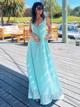 Vestido largo de algodón color turquesa, sin mangas, con escote en V y detalle de cordones con borlas. Presenta un estampado geométrico en el ruedo.