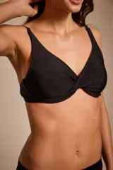 Top de bikini negro con breteles finos y detalle de nudo en el centro del busto.