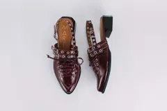 Sueco de cuero negro con cordones, ojales, hebillas y tira trasera regulable con elástico. Tiene taco cuadrado bajo.