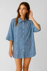 Túnica holgada con cuello camisero, manga 3/4 y cierre frontal con botones. Diseño a rayas verticales azules y blancas.