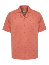 Camisa de manga corta color salmón con estampado de motivos florales, cuello cubano y cierre frontal con botones.