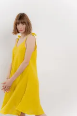 Vestido naranja de lino, corte midi, con escote en V y tirantes con moños.