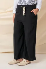 Pantalón ancho de hilo color negro, con cintura elastizada, cordón ajustable y bolsillos laterales.