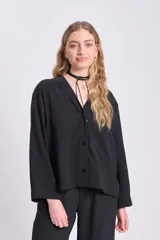Blusa negra de manga larga con cuello en V y cierre con botones.