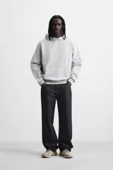 Sudadera con capucha gris confeccionada en tejido de algodón con interior rizo. Tiene manga larga, bolsillo frontal tipo canguro y acabados en rib.