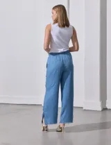 Pantalón celeste de lyocell, corte ancho, con cintura elastizada ajustable con cordón y ruedo desflecado con tajos laterales.