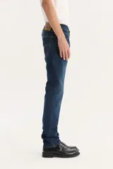 Pantalón de jean azul oscuro, corte slim fit, tiro medio y confección sin elasticidad.