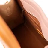 Cartera tote chica color rosa con detalles en marrón, confeccionada en símil cuero graneado. Tiene acceso con cierre, correa regulable y herrajes plateados. Se puede llevar en la mano o como bandolera.