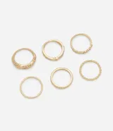 Set de seis anillos dorados con diferentes diseños: uno liso, uno con strass, uno con forma torcida, uno doble con strass y uno con strass artificial.