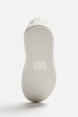 Zapatilla blanca de cordones fabricada en tejido transpirable de punto.