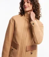 Saco color beige en polyvelour, con cuello alto, mangas largas, sisas desplazadas, cierre delantero y bolsillos con detalle en PU.