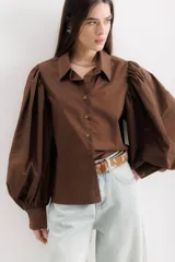 Camisa color beige de algodón con mangas abullonadas y cierre con botones.