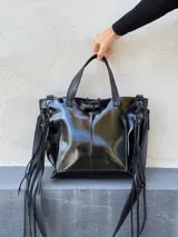 Cartera tipo tote de cuero color blanco con manchas doradas, doble asa corta y flecos de cuero en los laterales.