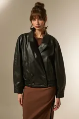 Campera estilo aviador de eco-cuero color negro, con cuello solapa, cierre cruzado con botones y elástico en la cintura y puños.