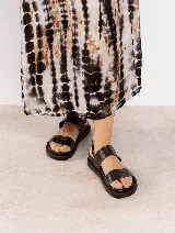 Sandalias de cuero negras con doble tira ancha y hebilla lateral.