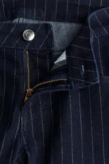 Jeans de cinco bolsillos en denim azul marino con leve stretch. Diseño de raya diplomática con hilos brillantes en la trama. Corte ajustado de cintura a cadera y acampanado desde la rodilla al bajo. Modelo de tiro bajo con cierre y botón.