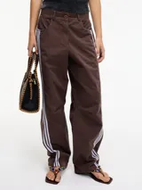 Pantalón slouchy marrón de tiro alto con cierre de botón y cremallera, pretina con pasacinto y rayas blancas laterales.