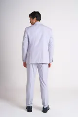 Traje de vestir celeste claro, compuesto por saco de dos botones con solapa de muesca, bolsillo de ojal en el pecho y bolsillos con solapa en los laterales, y pantalón de vestir de corte recto con ruedo arremangado.