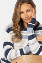 Buzo tejido a rayas horizontales en tonos azul marino, celeste, beige y blanco. De corte holgado y mangas largas, confeccionado en algodón.