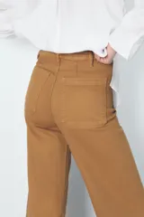 Pantalón de jean de tiro alto color negro con pierna ancha, bolsillos delanteros y traseros, y cierre frontal con cremallera y botón metálico.