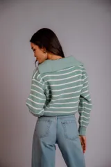 Sweater de punto color beige con rayas horizontales blancas, cuello polo con cierre de cremallera y mangas largas.