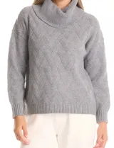 Buzo de punto grueso color beige, con cuello volcado y textura en relieve. Tiene mangas largas de corte hombro caído y puños anchos.