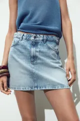 Minifalda de jean celeste con cinco bolsillos, efecto lavado y cierre frontal con cremallera y botón metálico.