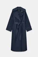 Trench oversize de Zara Woman Collection, color azul marino, confeccionado en hilatura con mezcla de algodón. Presenta cuello solapa, manga larga ajustable con trabillas, bolsillos delanteros y cinturón del mismo tejido con lazadas. Destacan los pespuntes marcados a tono y el cierre frontal cruzado con botones.