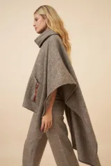 Poncho de lana color marrón con cuello alto, mangas 3/4 y bolsillo lateral con detalle de botones de cuero.