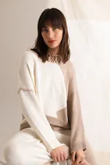 Sweater tejido color crema con mangas ranglán color beige y cuello redondo.