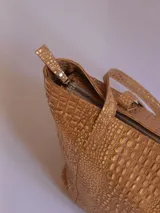 Bolso tote de cuero color marrón con textura tipo piel de cocodrilo, cierre superior con cremallera, bolsillo interior y llavero.