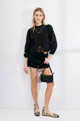 Short de jean negro con ruedo desflecado y tajo en los laterales.