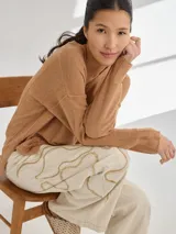 Pantalón de lino color beige con bordado artesanal de líneas onduladas en color marrón.