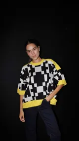 Sweater de punto con mangas cortas, estampado geométrico en blanco y negro, y ribetes amarillos en cuello, puños y ruedo.