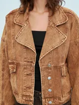 Campera color marrón claro con cuello solapa, cierre frontal con botones y bolsillos con solapa en el pecho.