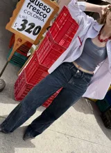 Pantalón jean azul oscuro, de corte wide leg y tiro medio. Presenta detalles de costuras diagonales en la parte superior.