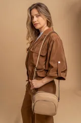 Bandolera color beige de diseño compacto, con correa regulable, bolsillos frontales y cierre superior.