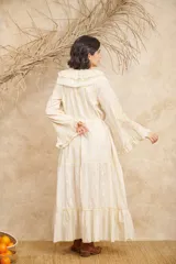 Vestido largo color crema con bordados florales en tonos pastel, escote en V con volados, mangas largas acampanadas y abertura frontal. Incluye lazo ajustable en la cintura.