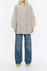 Gabardina corta oversize color gris, con cuello ajustable y cierre frontal de botón a presión.