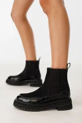 Botas Chelsea de cuero color negro, con elástico lateral, suela track y detalle de pespuntes en la puntera.