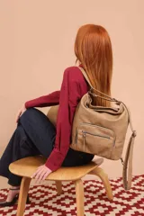 Cartera mochila color tostado, símil cuero, con compartimiento principal amplio y bolsillos frontales con cierre. Tiene correas ajustables para usar como mochila y asa superior para llevar al hombro.