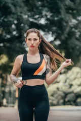 Top deportivo negro con breteles anchos, escote redondo y detalle de franja diagonal naranja y blanca en el frente.
