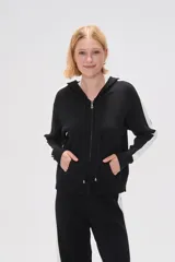 Campera negra de tejido de punto con capucha, cierre frontal y bolsillos tipo canguro. Presenta una franja blanca vertical en cada manga.